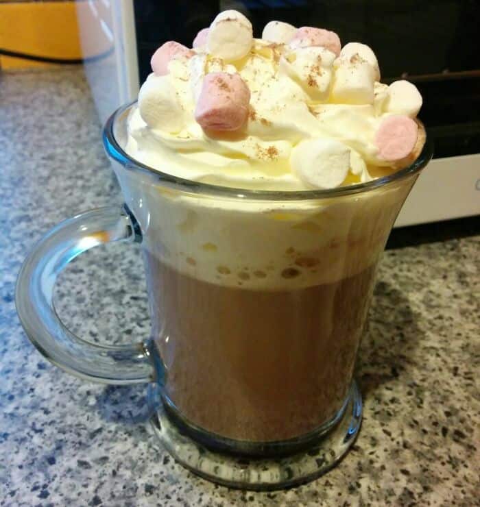 Delicious hot chocolate topped with whipped cream and colorful marshmallows, perfect for a cozy, who.
