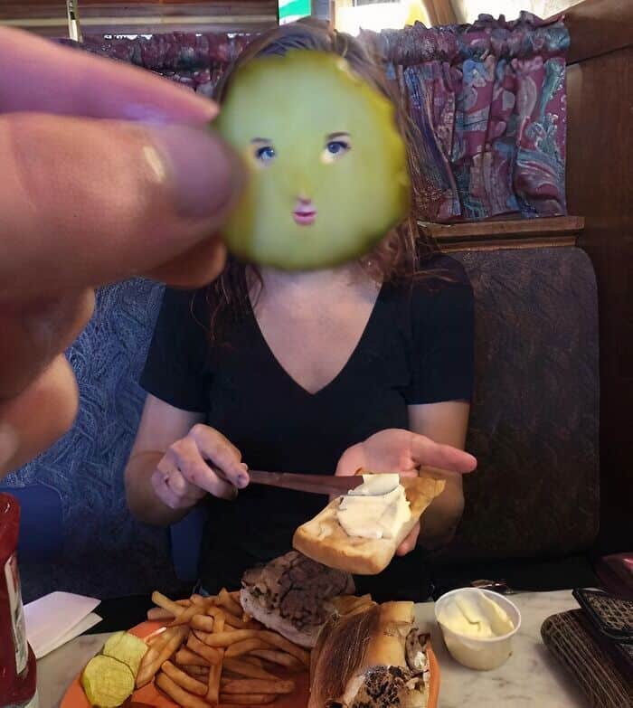 Woman holding a slice of bread with a face mask in a cozy restaurant.