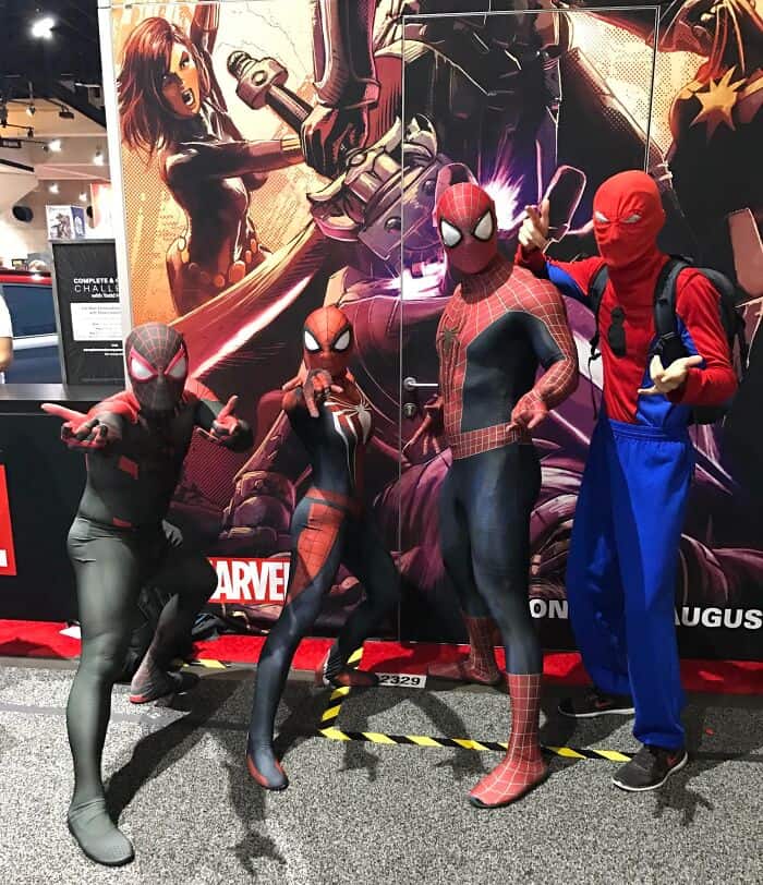 Spider-Man, Spider-Gwen, and ninja costume characters posing at a comic convention.