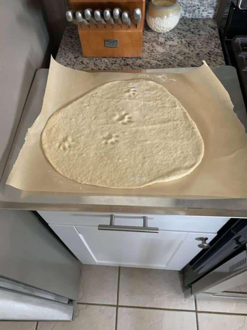 Fresh pizza dough on parchment paper, ready to be baked into a delicious homemade pizza.