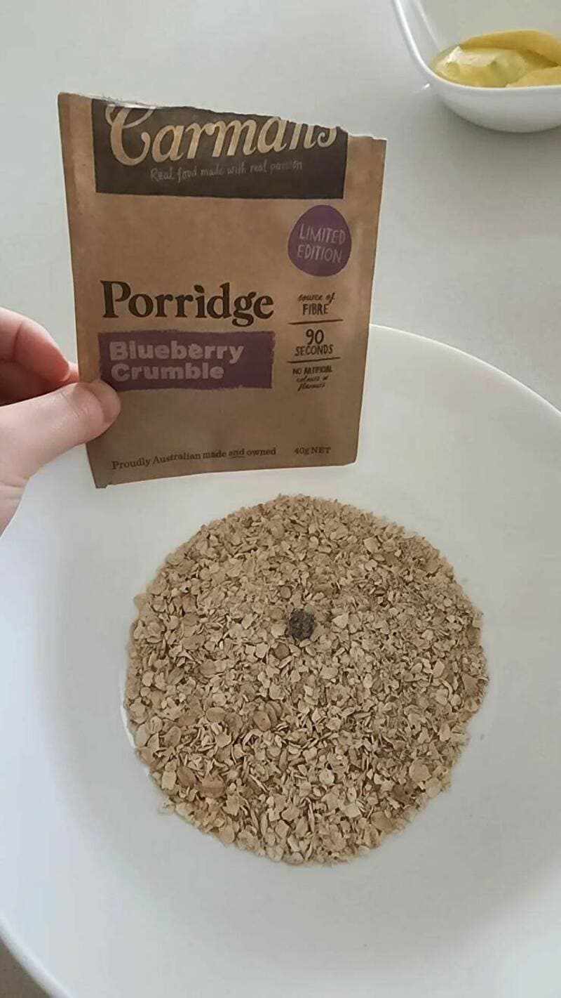 Porridge with blueberry crumble in a white bowl, ready to serve.