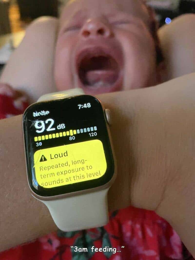 Baby crying loudly with Apple Watch showing 92 dB noise level, in a humorous scene.