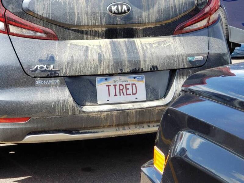 Car with a "TIRED" license plate covered in dirt and grime.