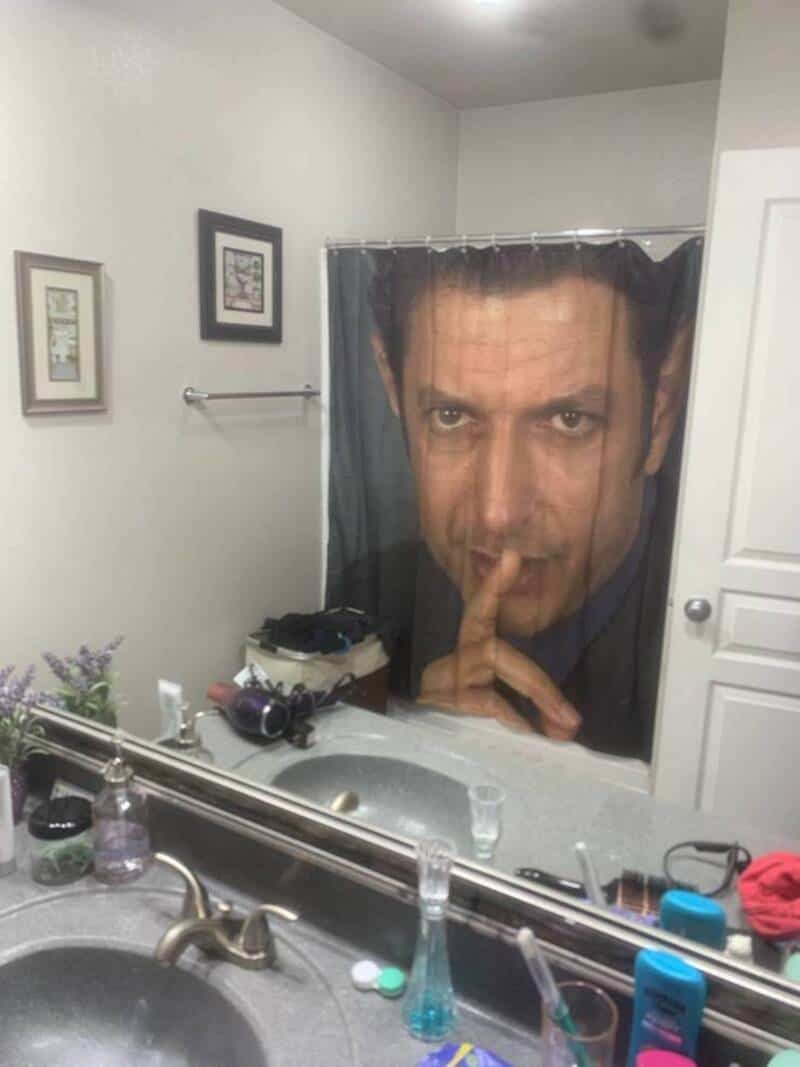 Humorous bathroom mirror with a large face curtain for fun photos.