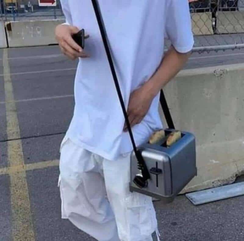 Person holding a bagel toaster with bagels outside.