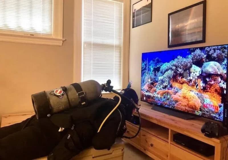 Person watching TV with scuba gear in living room.