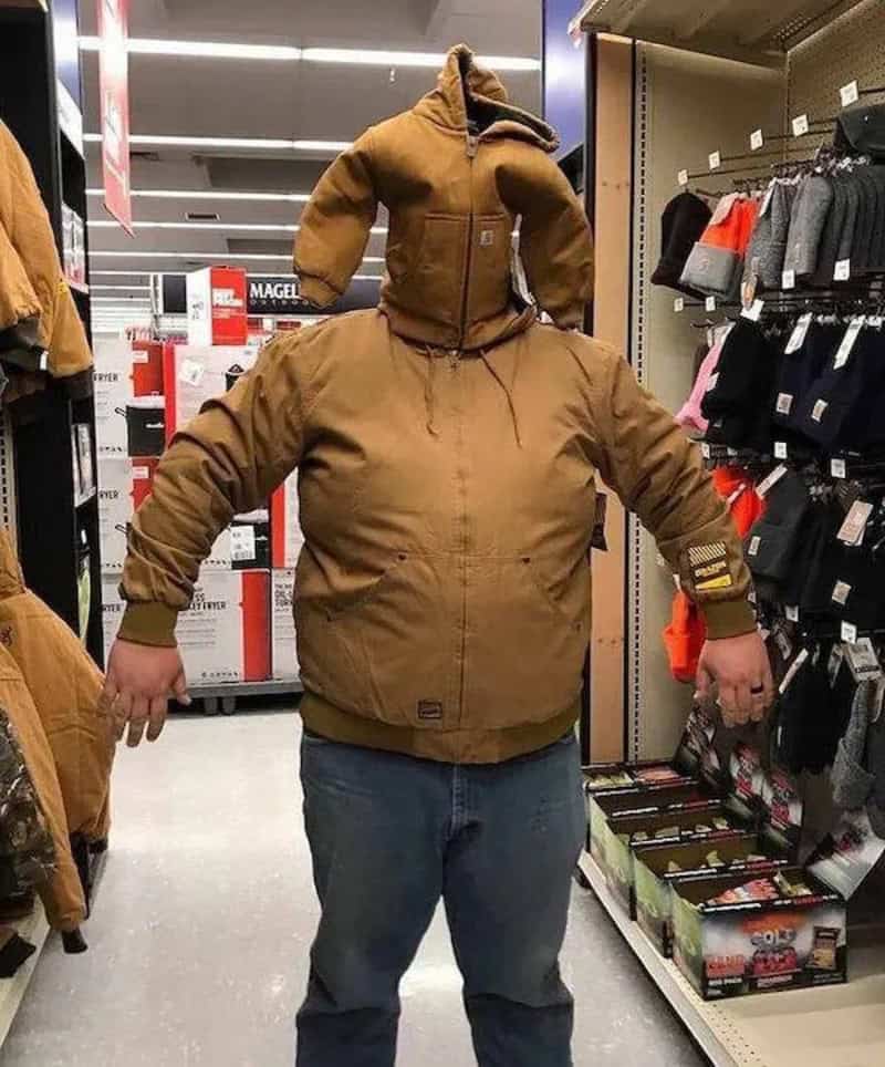 Winter jacket with a detachable hood and a small stuffed animal head on top, displayed in a retail s.