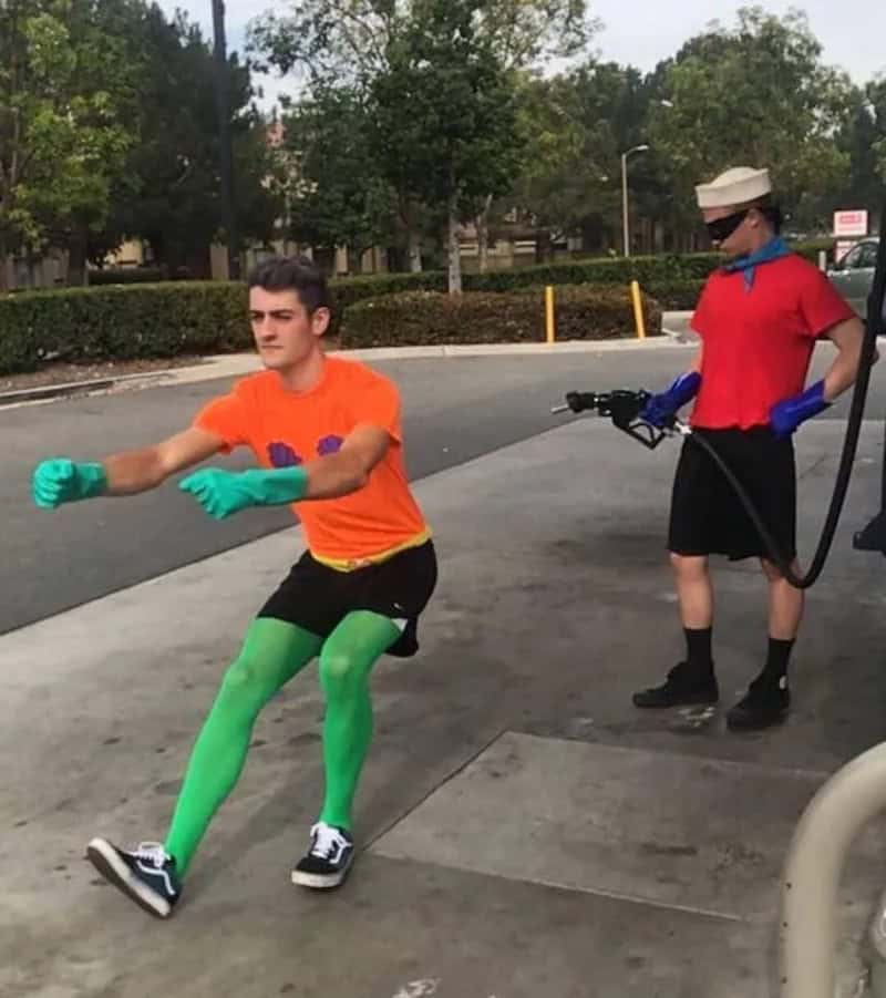 Playful young man in bright clothing and green tights dancing on the sidewalk.