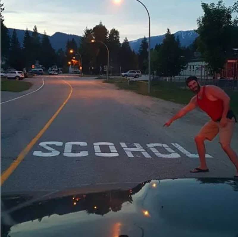 Funny man pointing at school crossing sign on the road during sunset.