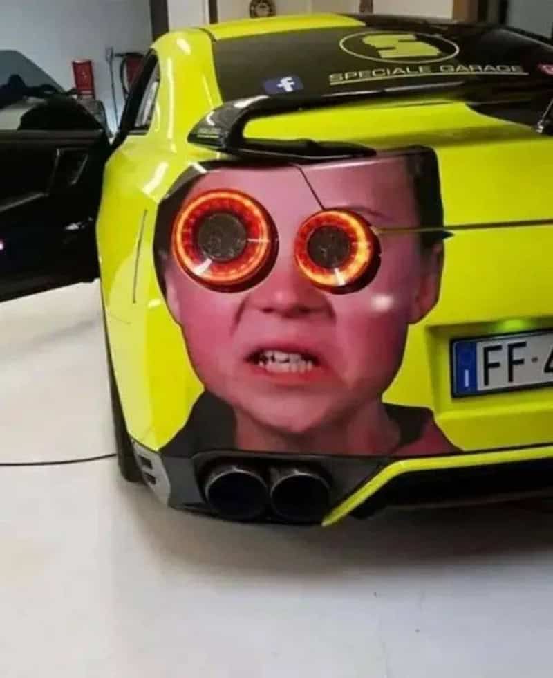 Car with a child's face and glowing taillights as eyes, creating a humorous and eye-catching vehicle.