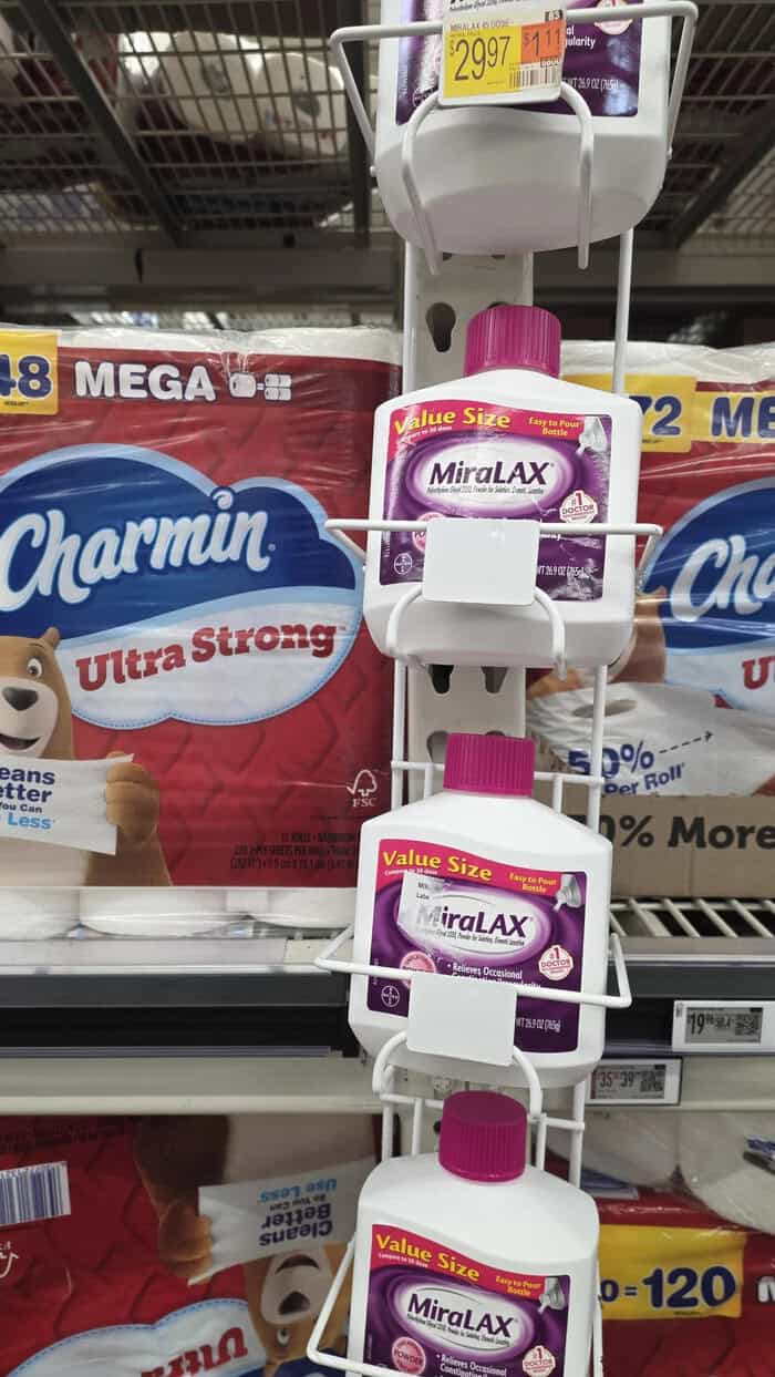 MiraLAX laxative bottles on store shelf with Charmin toilet paper in background.