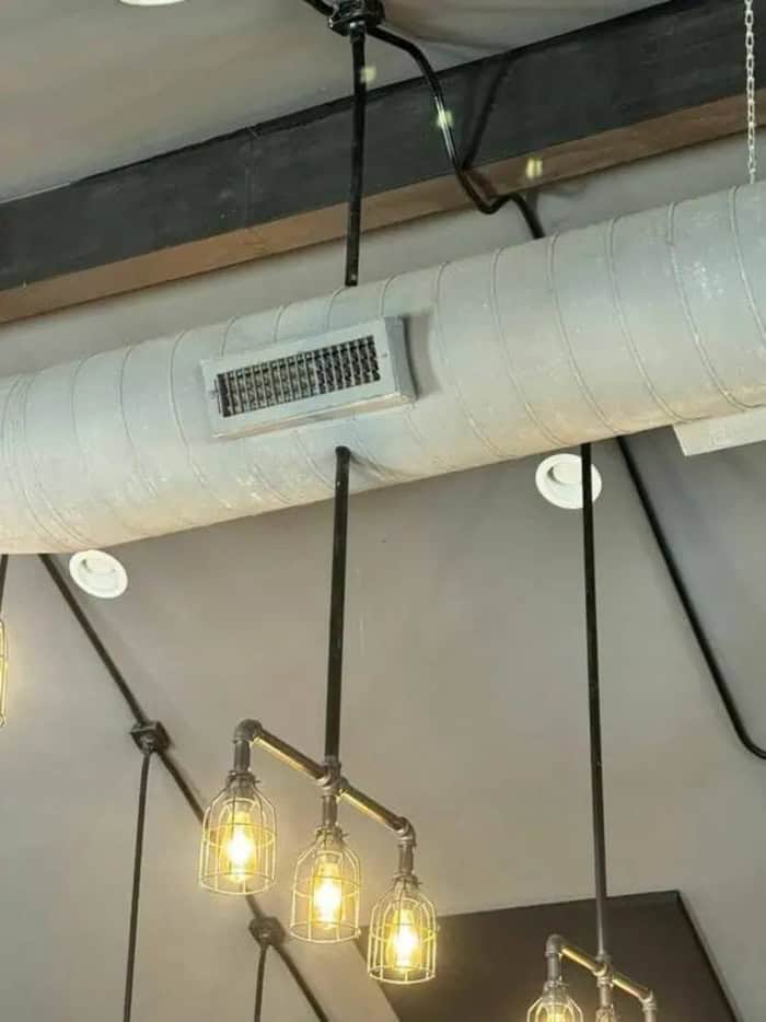 Industrial-style hanging light fixture with three bulbs and exposed piping.