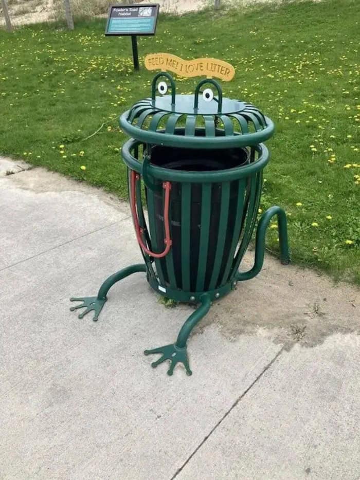 "Welcome! I love Litter" trash can designed as a frog with a smiling face, sitting on a sidewalk nea.