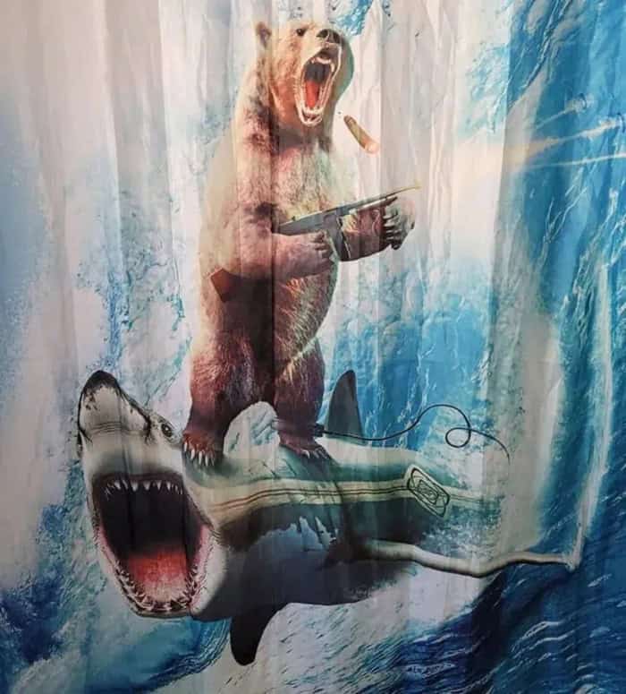 A bear holding a gun and a sausage, standing on a shark with an open mouth.