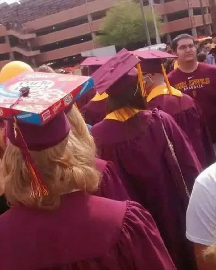 Graduates in maroon caps and gowns at an outdoor commencement ceremony.