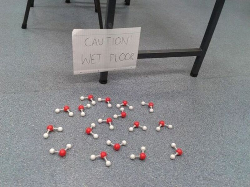 Humorous wet floor sign with scattered water molecules, highlighting a funny and random picture perf.