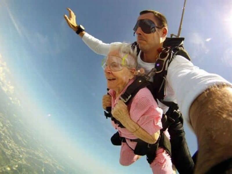 Skydiving with elderly woman and instructor for fun and adventure.