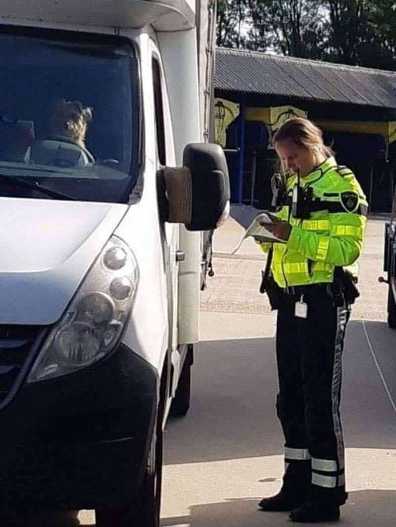 Police officer inspecting a van during a traffic stop.
