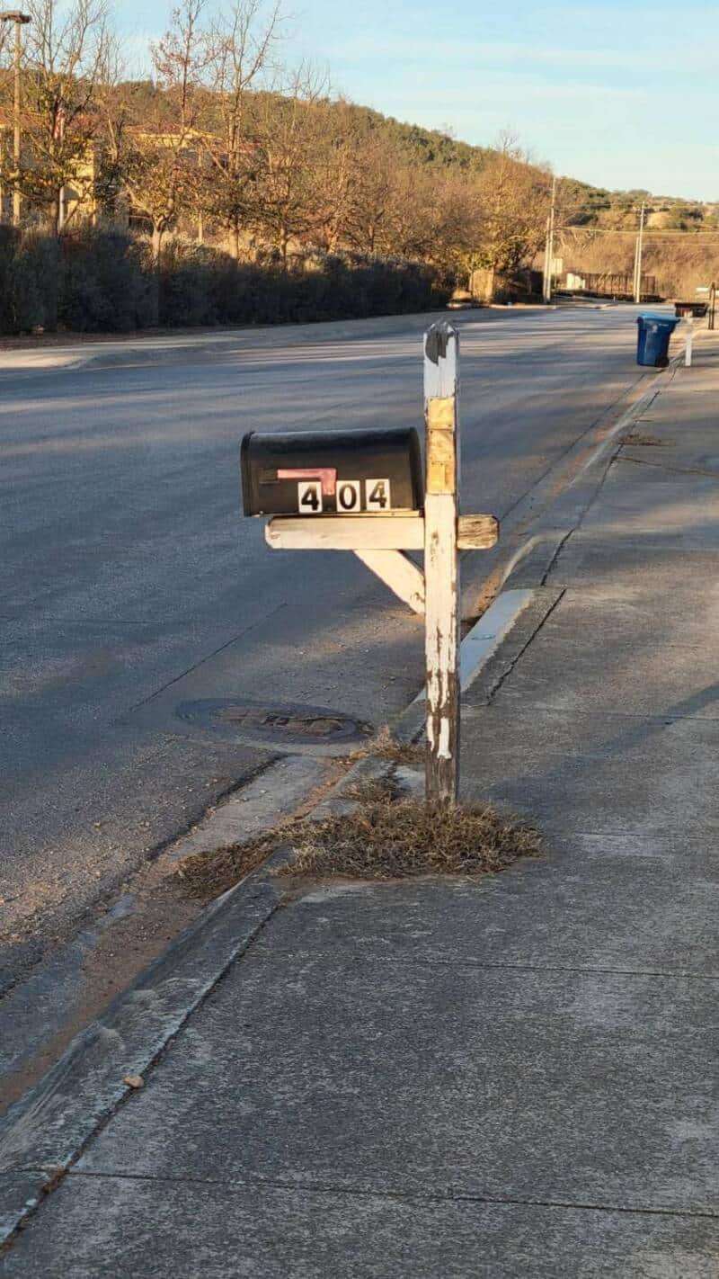 Funny mailbox displaying "404" error message on a suburban street.