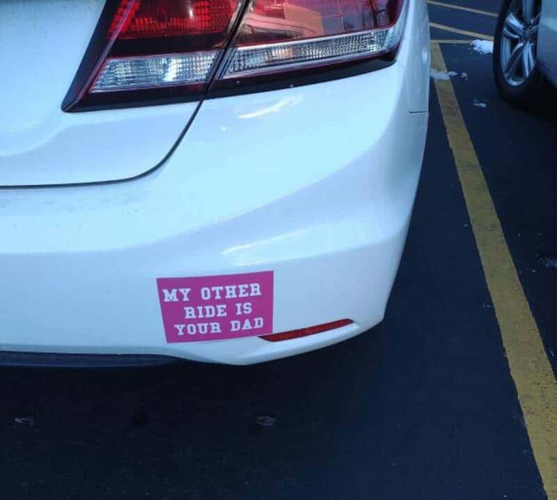 Humorous car bumper sticker reading "My Other Ride is Your Dad" on a white vehicle.