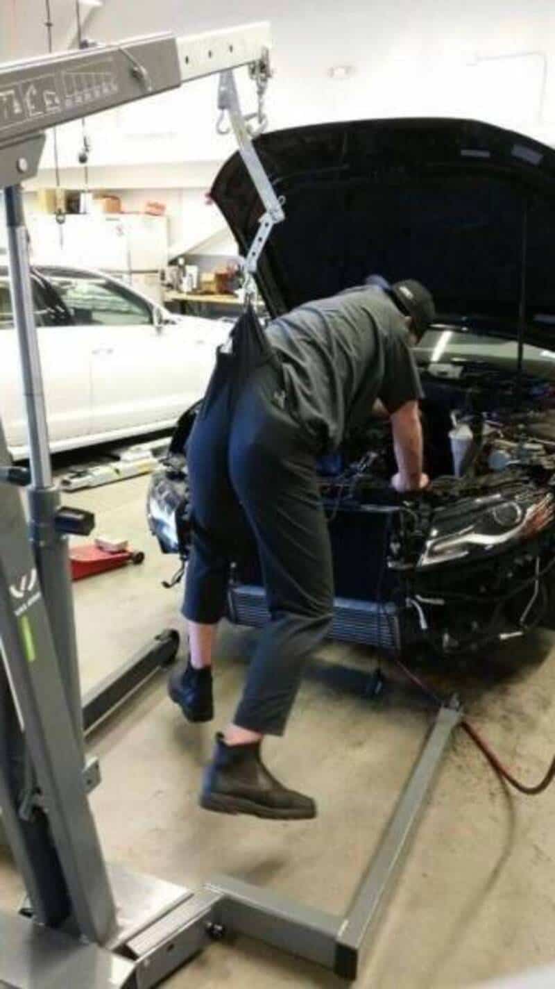 Mechanic inspecting car engine in auto repair shop.