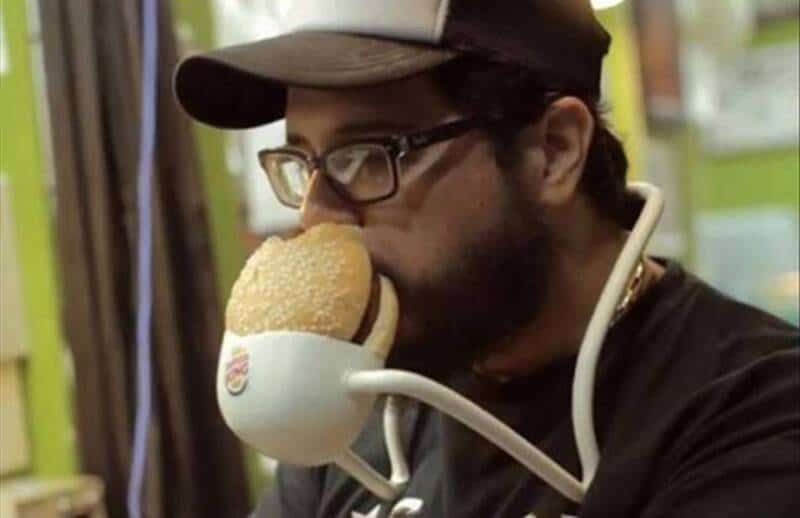 Man drinking coffee from a mug shaped like a face, humorous scene.
