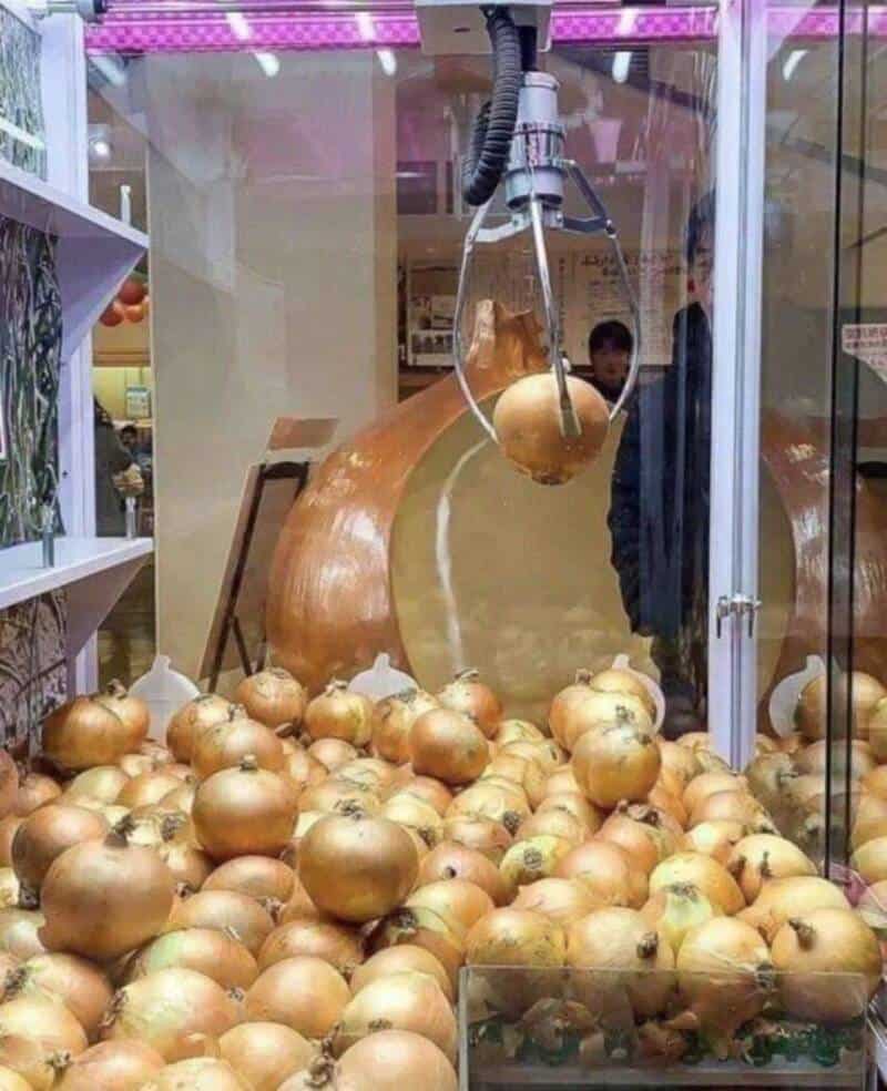 Golden onion claw machine with a large onion inside, surrounded by many golden onions, in a shopping.