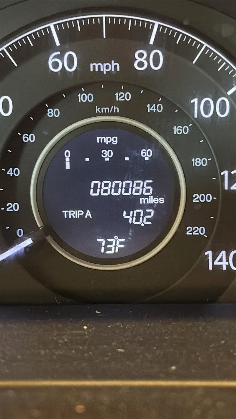 Speedometer and digital display showing mileage, trip distance, and temperature in a vehicle dashboa.
