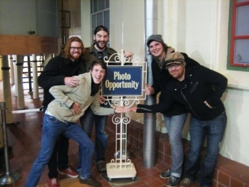 Group of friends posing with a "Photo Opportunity" sign, smiling and having fun indoors.