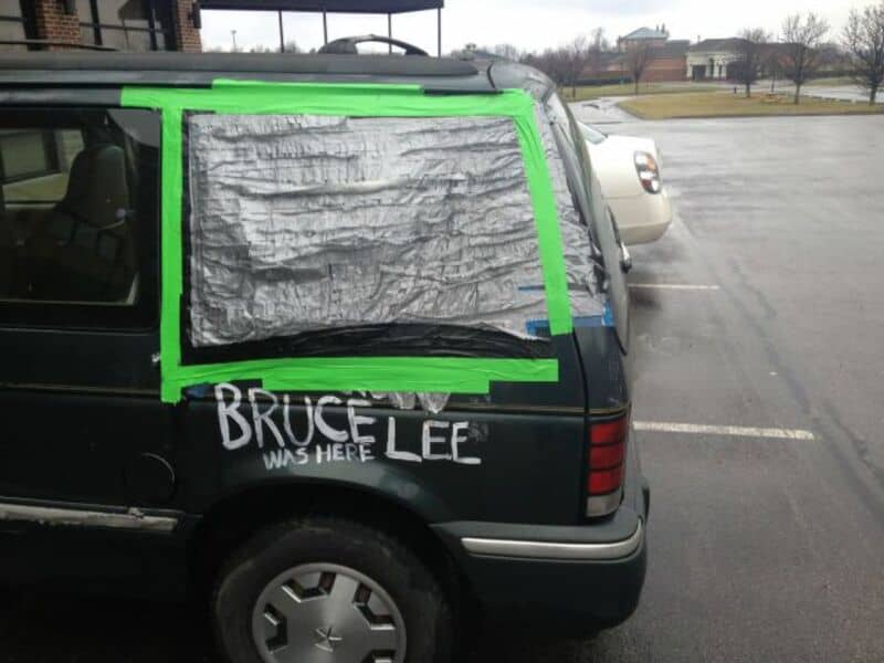 Custom car window cover with "Bruce Lee" written on the back, in a parking lot.