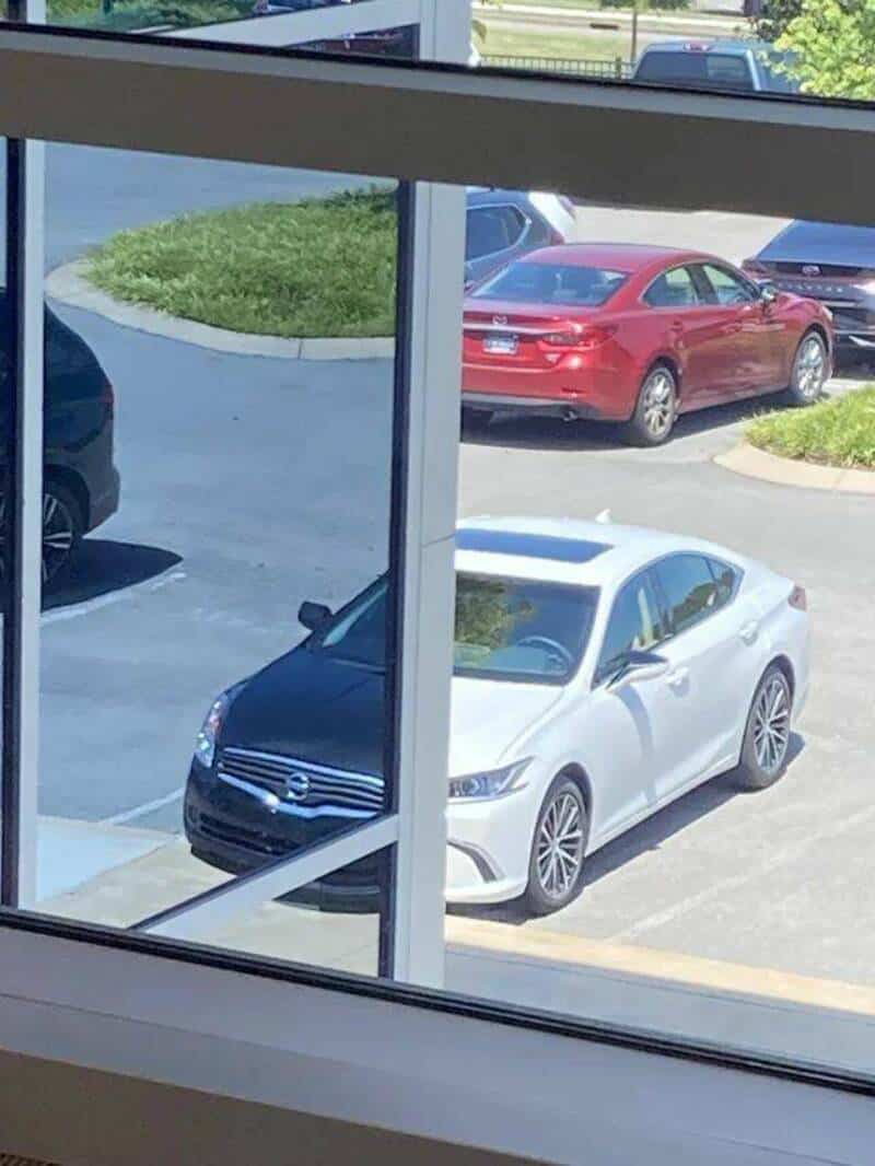 Car parked outside viewed through window in parking lot.