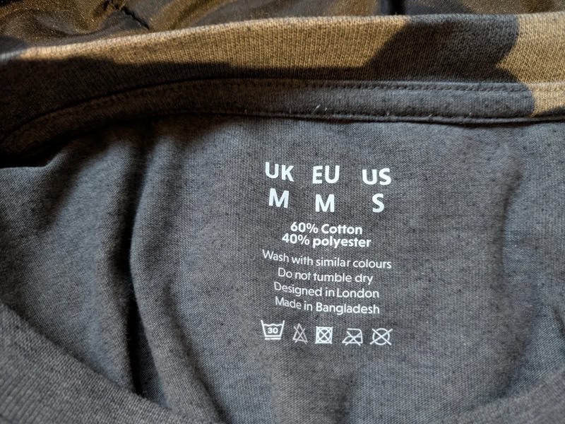 Cotton-polyester blend T-shirt label showing size and care instructions.