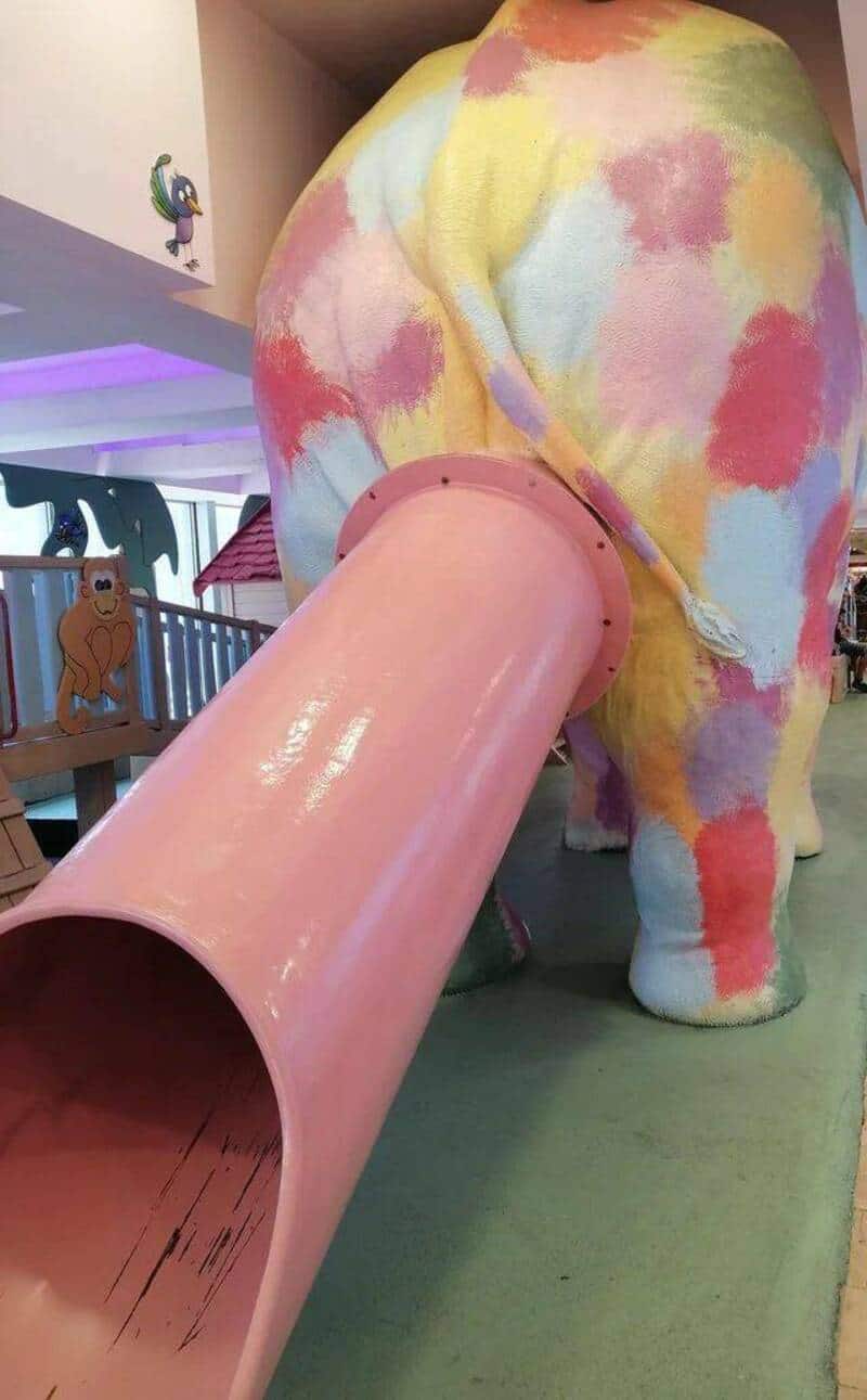 Pink elephant slide with colorful tie-dye pattern, indoor playground attraction.