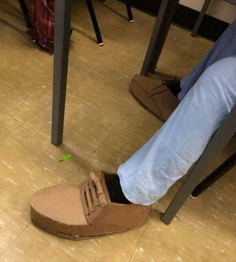 Close-up of a casual brown shoe worn by a person sitting at a desk.