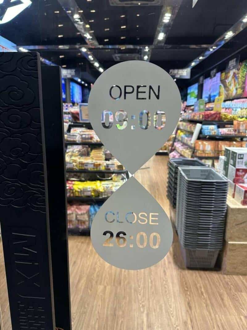 Store hours sign showing open at 9:00 and close at 26:00 in a supermarket.