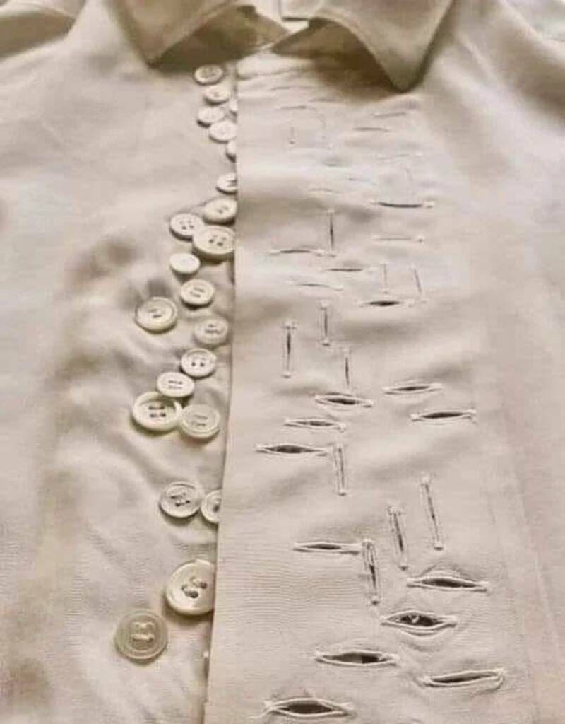 Close-up of a beige shirt with decorative buttons and intentional rips for a trendy, distressed look.