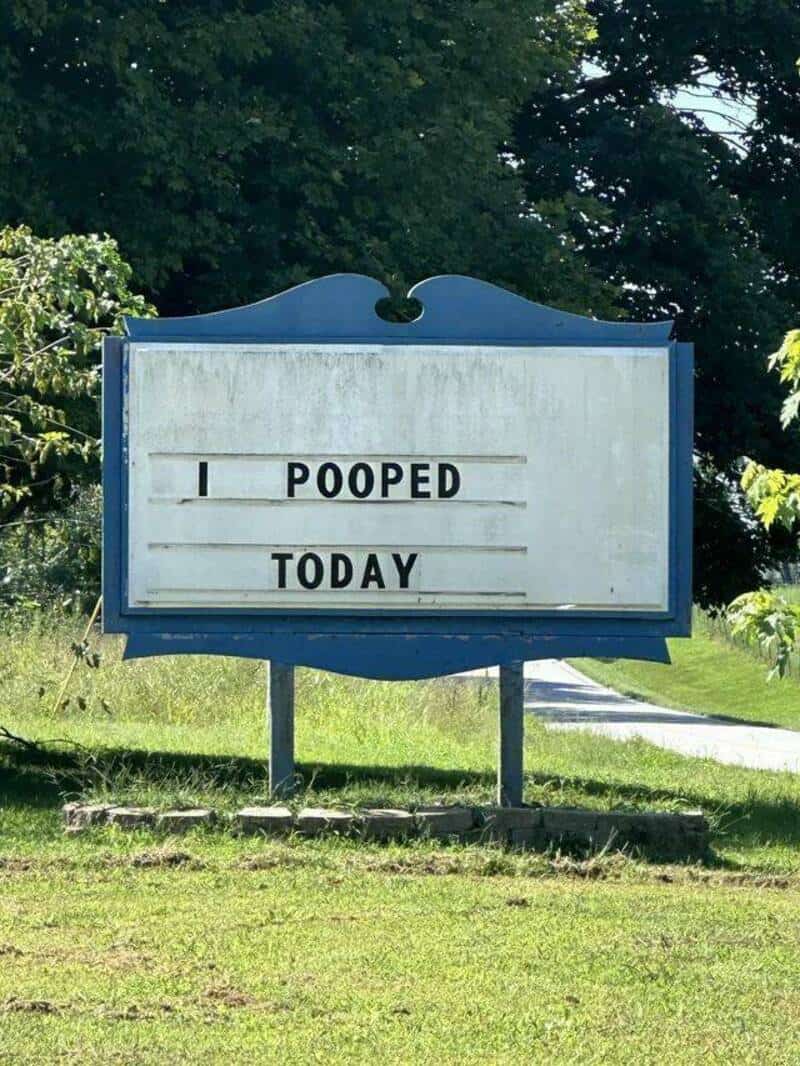 Humorous outdoor sign reading "Pooped Today" in a park setting.