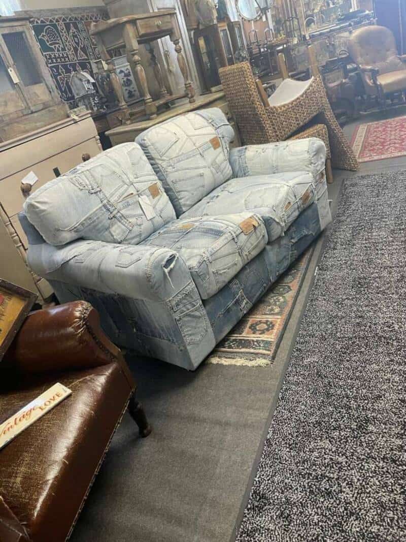 Vintage distressed fabric sofa with torn upholstery in a furniture showroom.