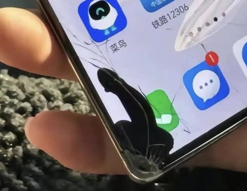 Broken smartphone with cracked screen displaying app icons, close-up shot.