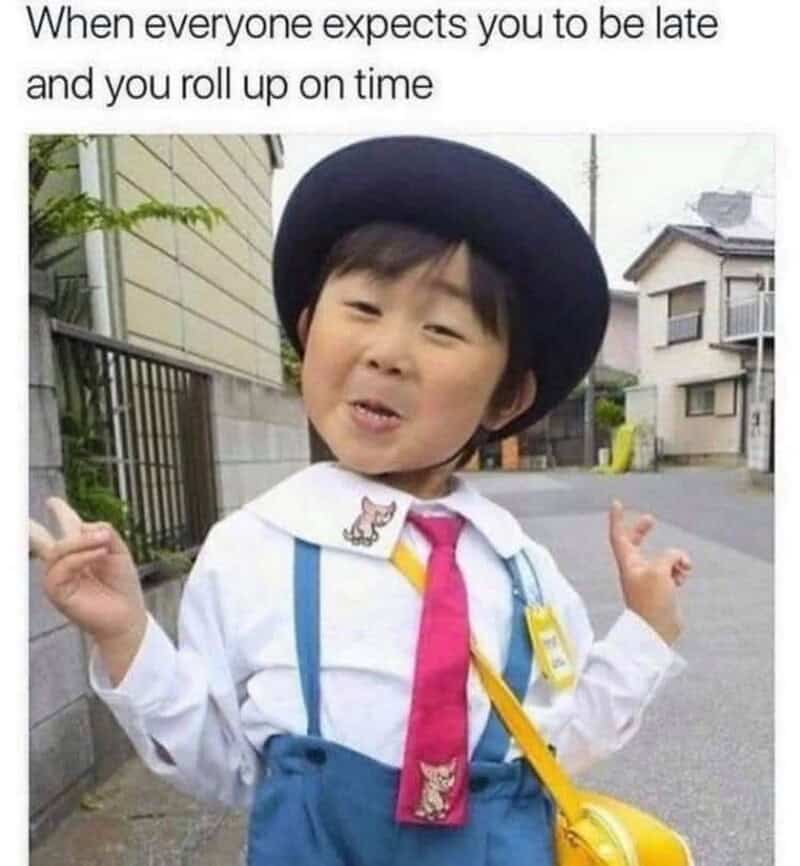 Child in school uniform making a funny face, wearing a hat and suspenders.