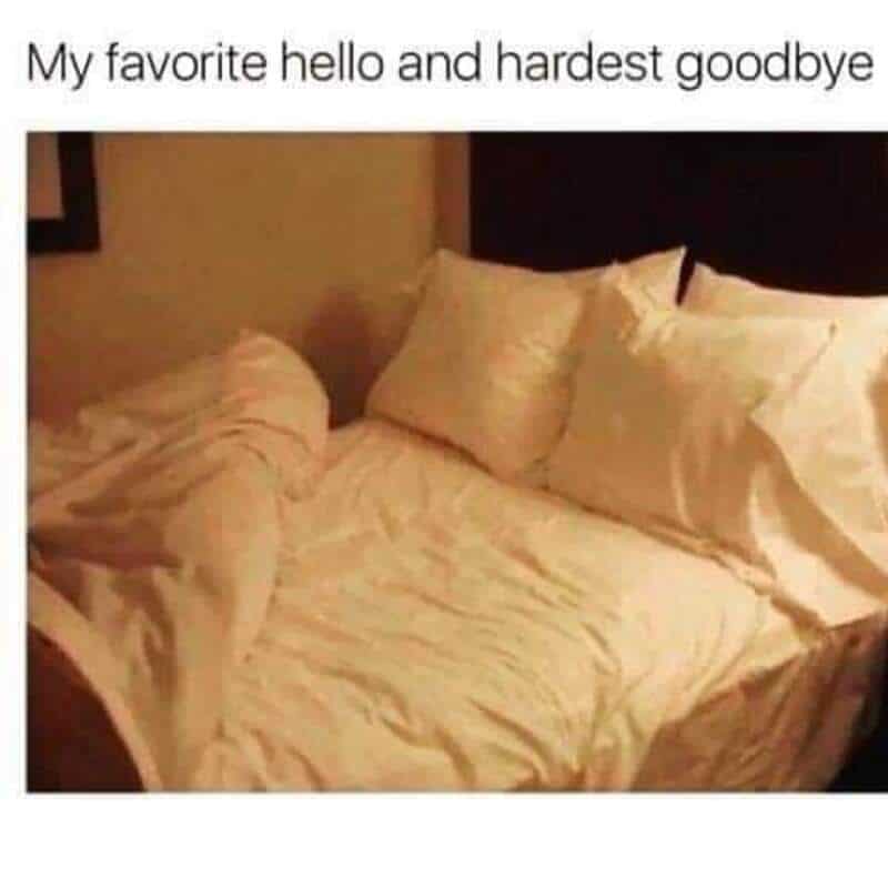Cozy bed with rumpled sheets and pillows in a warmly lit room.