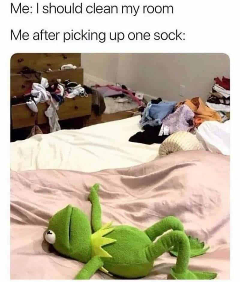 Cluttered bedroom with sock pile and plush frog toy on bed.