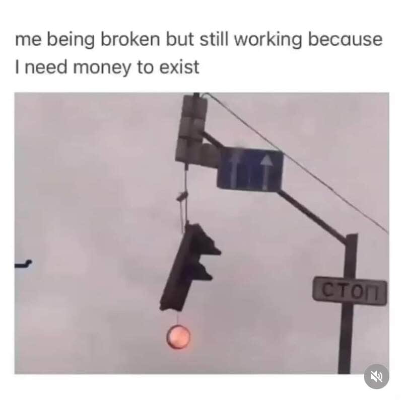 Traffic light hanging from a wire with a humorous caption about being broke but still working.