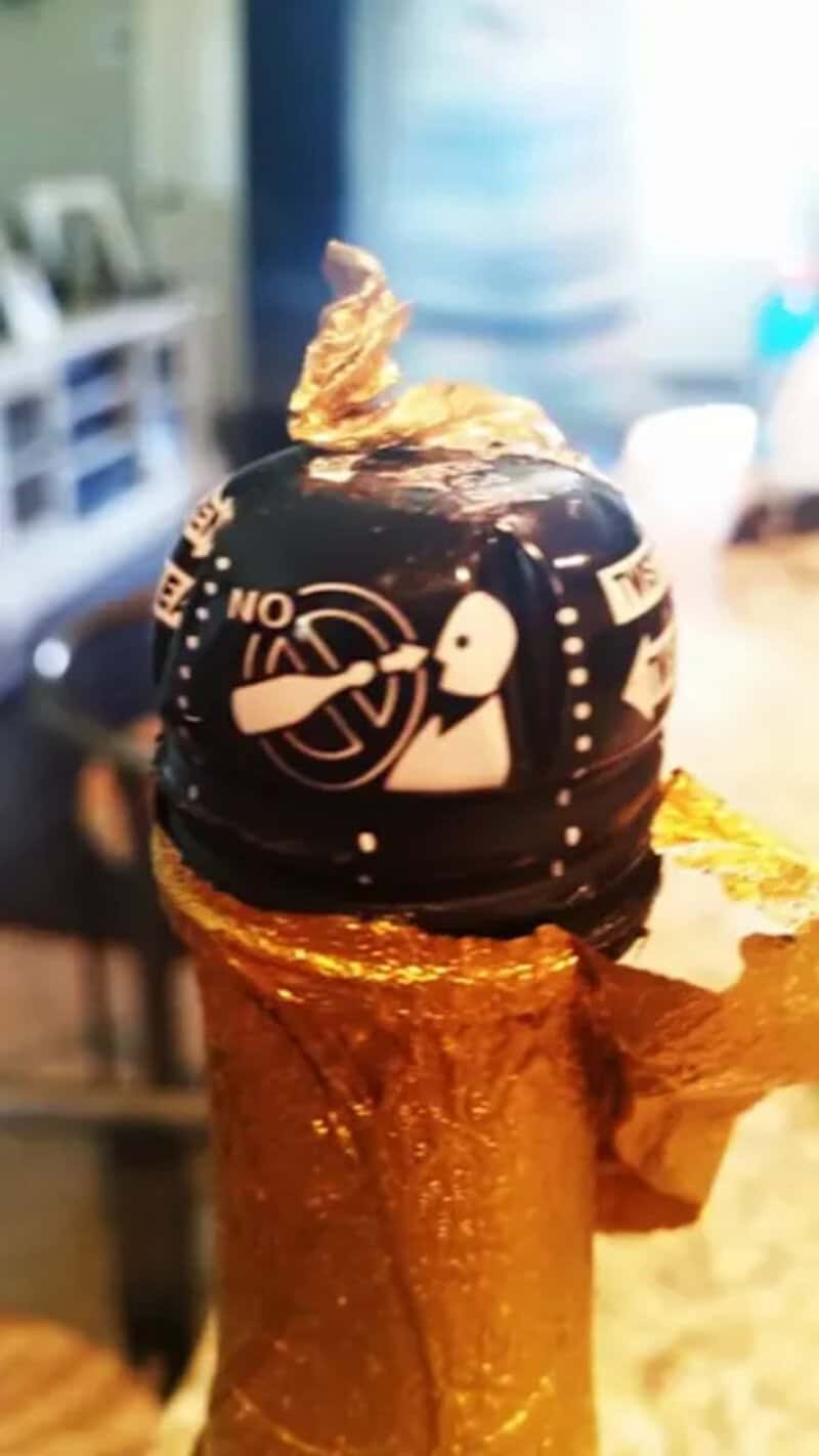 Chocolate cake with gold leaf and artistic black and white design, perfect for special occasions.