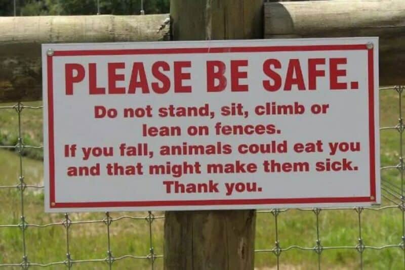 Warning sign on a fence advising safety precautions and animal safety.