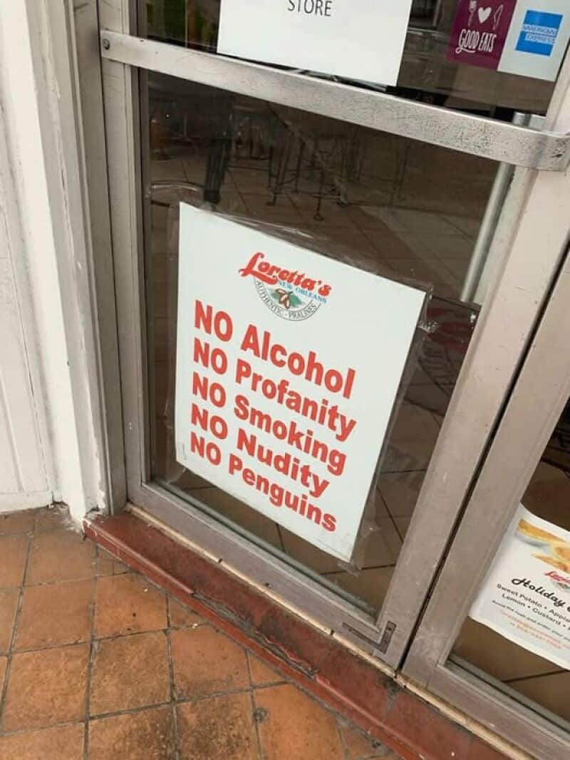 Sign on restaurant door prohibiting alcohol, profanity, smoking, nudity, and penguins.
