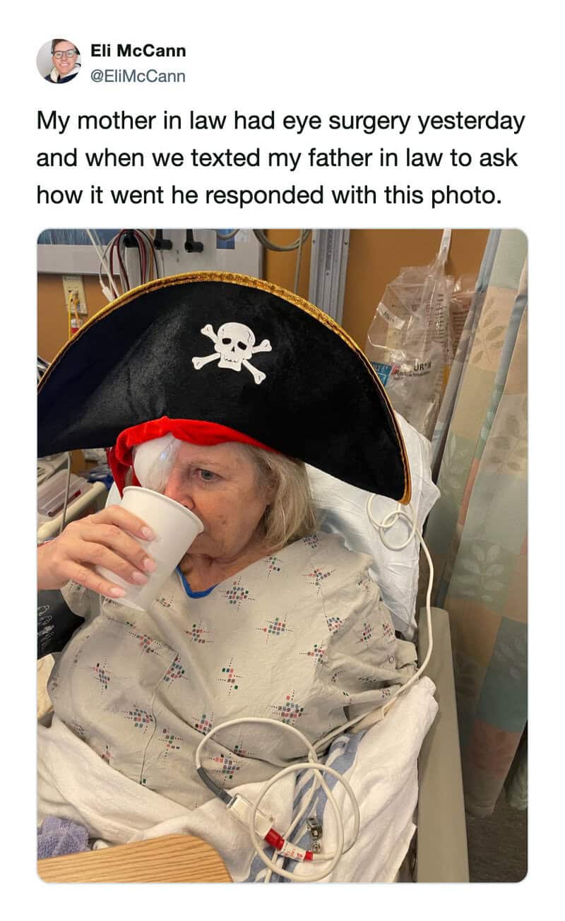 Pirate hat with skull design worn by elderly woman in hospital bed, holding a cup, after surgery.