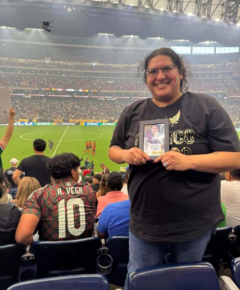Happy woman holding framed photo at soccer match.