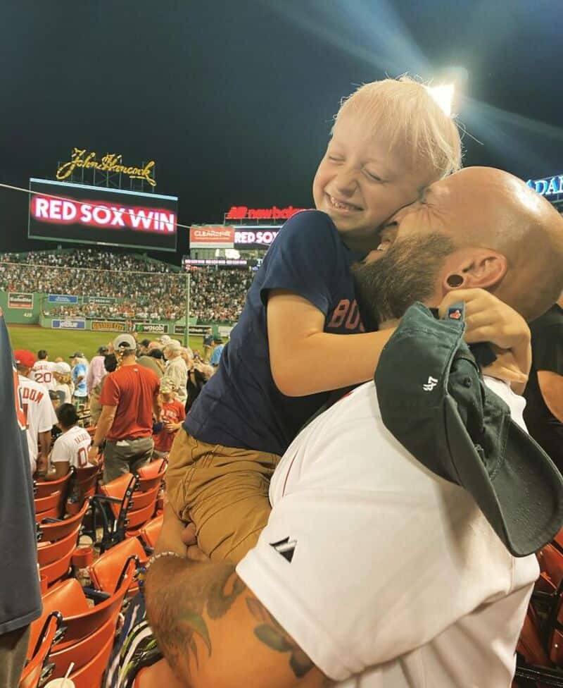 Happy child embracing adult during a baseball game at Fenway Park.