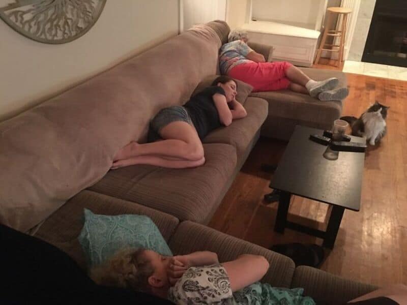 Family relaxing on sofa with pets, kids and dog resting in living room.